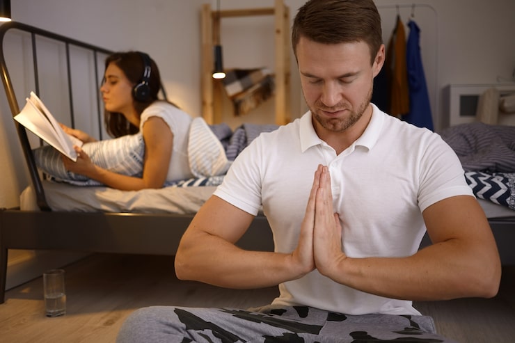Man sitting peacefully with hands in prayer, reflecting on Christian values at home.