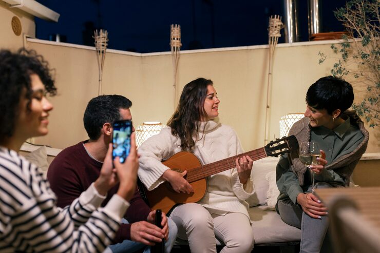 Friends enjoying live guitar music on a rooftop at night.